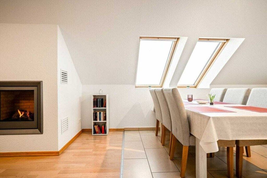 Een eethoek met een open haard, een boekenkast en een tafel gedekt voor vier personen.