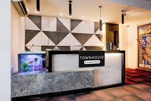 Una recepción con un cartel que dice 'TOWNHOUSE', un acuario y una pared decorativa con patrones geométricos.