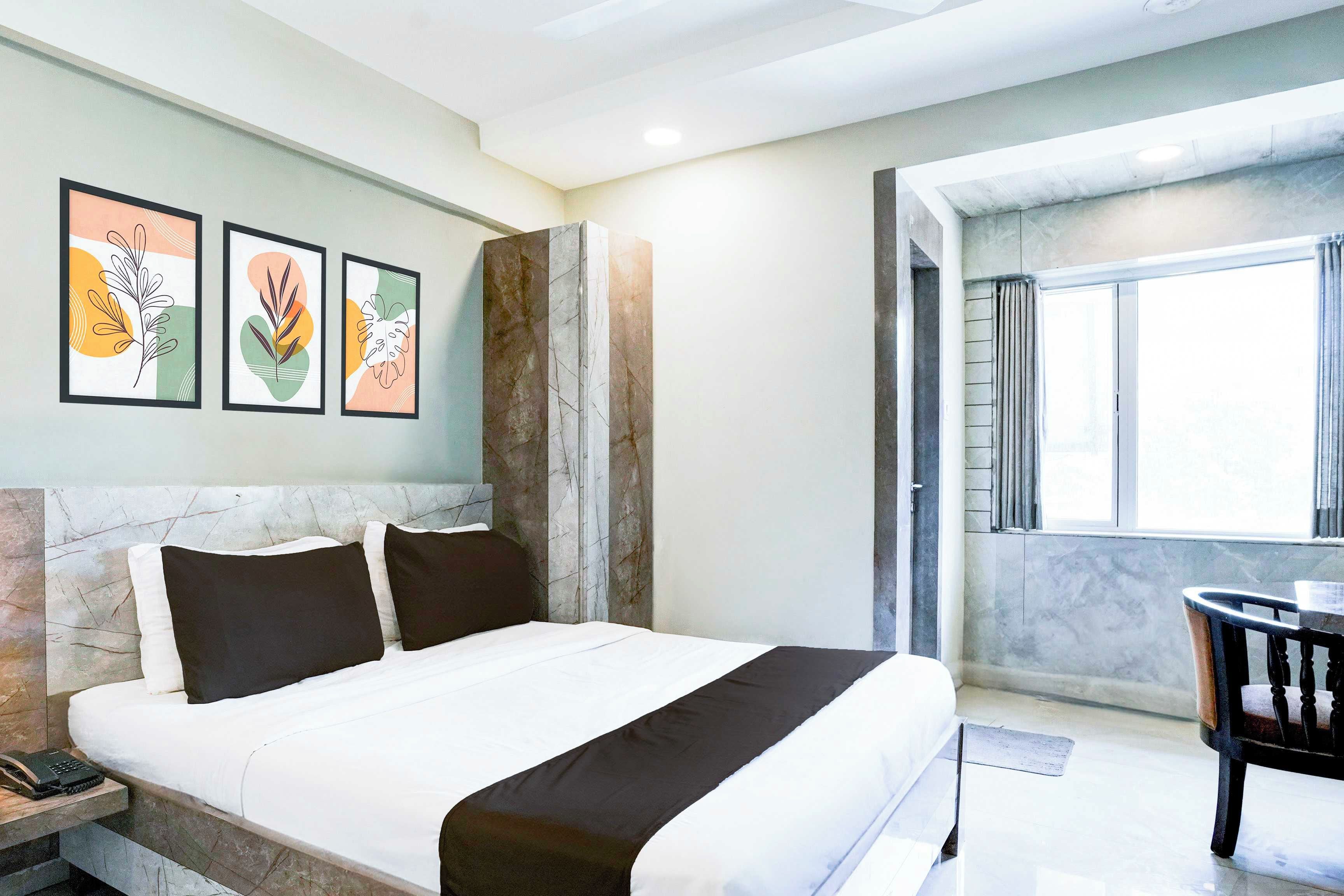 Habitación de hotel con cama, escritorio y silla. Tres cuadros decoran la pared.