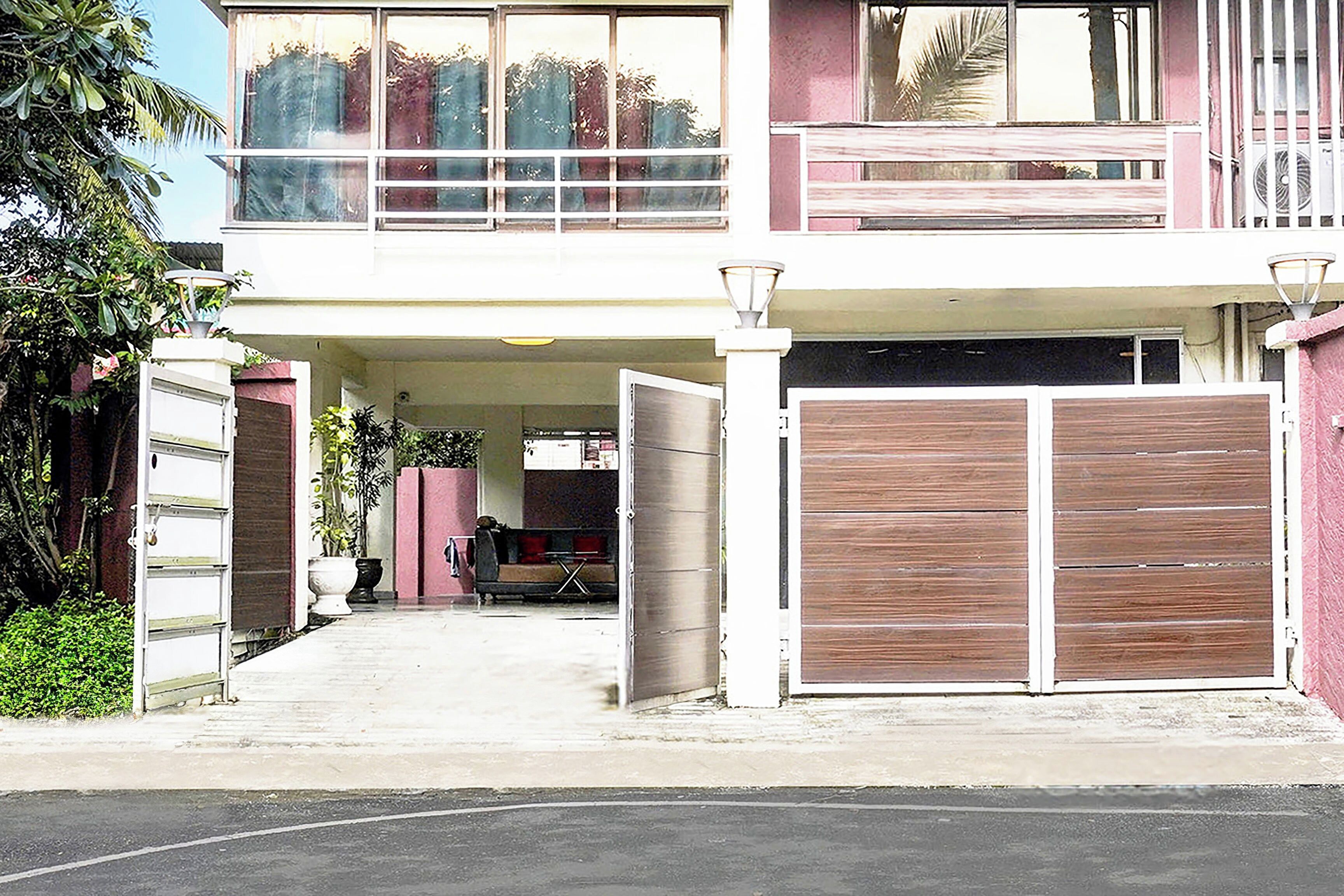 A two-story building with a covered entrance, a balcony, and a gated driveway.