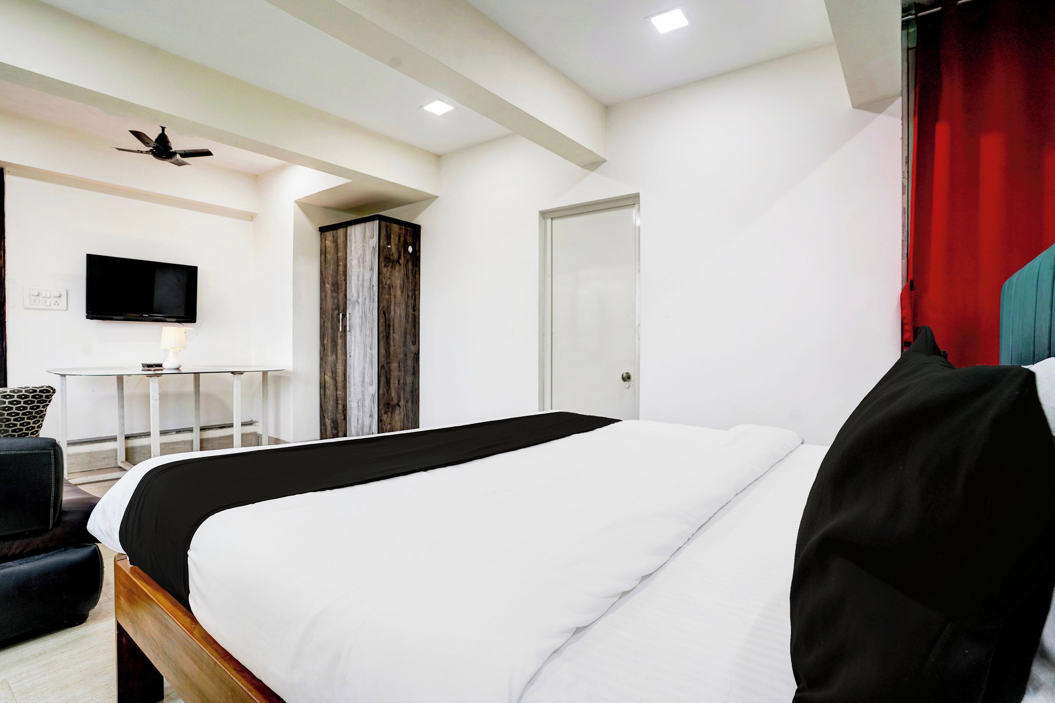 Una habitación de hotel moderna con una cama, un escritorio, un televisor y un armario.