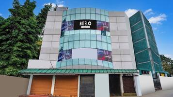 Un hotel con fachada curva, múltiples ventanas y un letrero que indica que es un establecimiento de servicios para empresas.