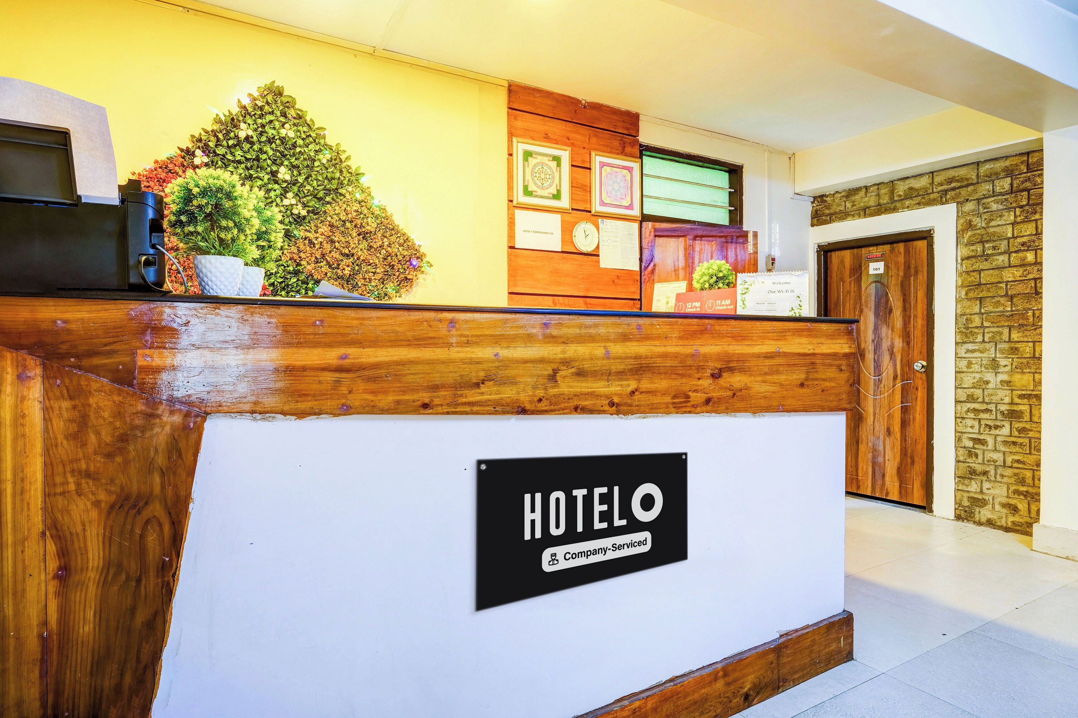 Ein Hotel-Rezeptionsschalter mit einem 'HOTELO'-Schild, einer Uhr und einem Hinweis auf kostenloses WLAN.