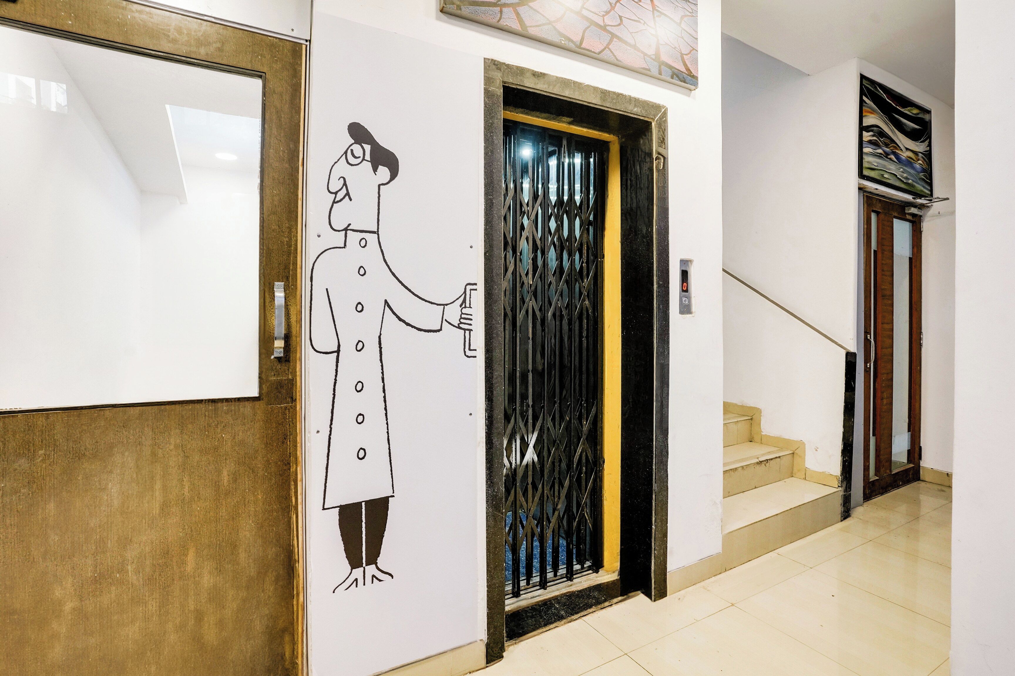 A hallway with a door featuring a metal gate, a staircase, and a wall-mounted artwork.