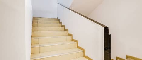 A staircase with beige steps and a black handrail, leading to a landing.