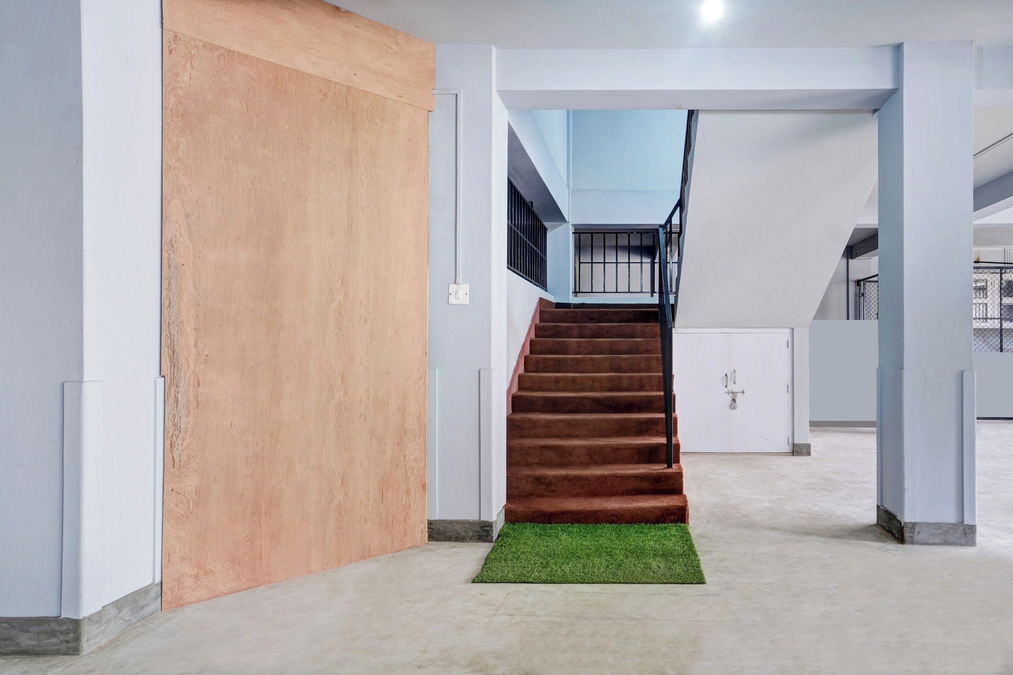 Un escalier menant à l’étage supérieur, avec un palier recouvert de moquette et une rambarde en métal.