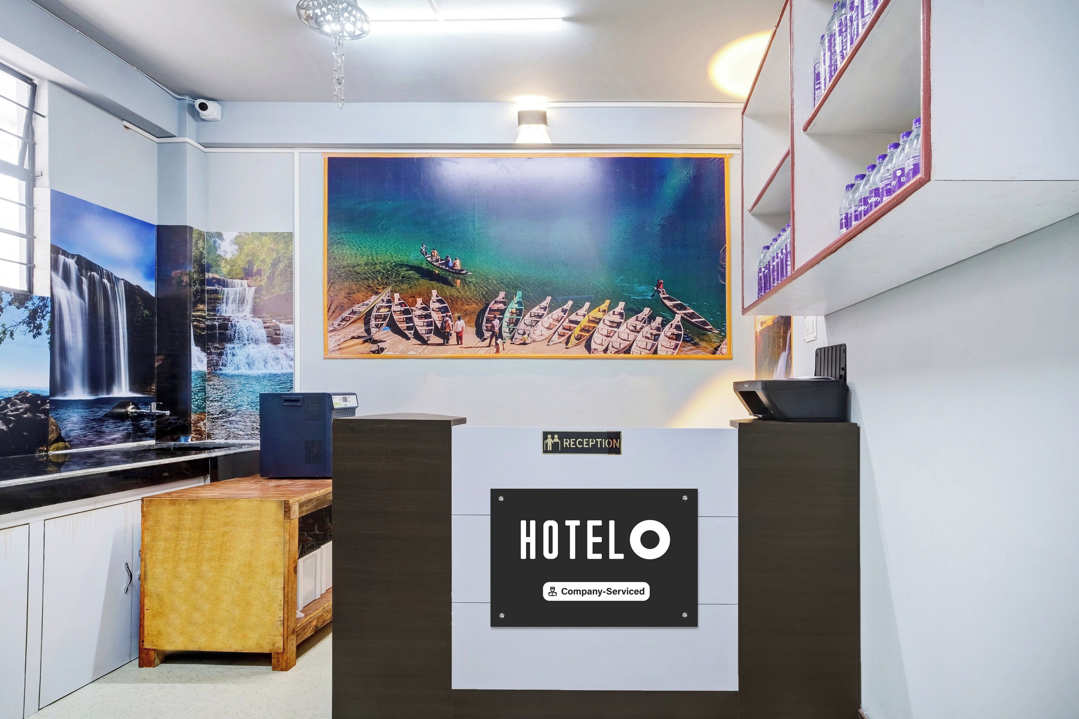 A reception area with a large painting of boats on water, a reception desk, and a sign indicating 'Company-Serviced'.