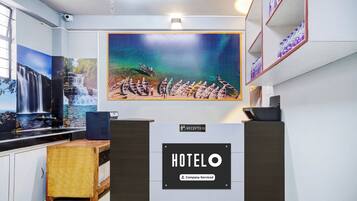 A reception area with a large painting of boats on water, a reception desk, and a sign indicating 'Company-Serviced'.