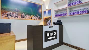 Un comptoir d’accueil avec une enseigne « HÔTEL », une imprimante Canon et un distributeur d’eau placés sur des étagères.