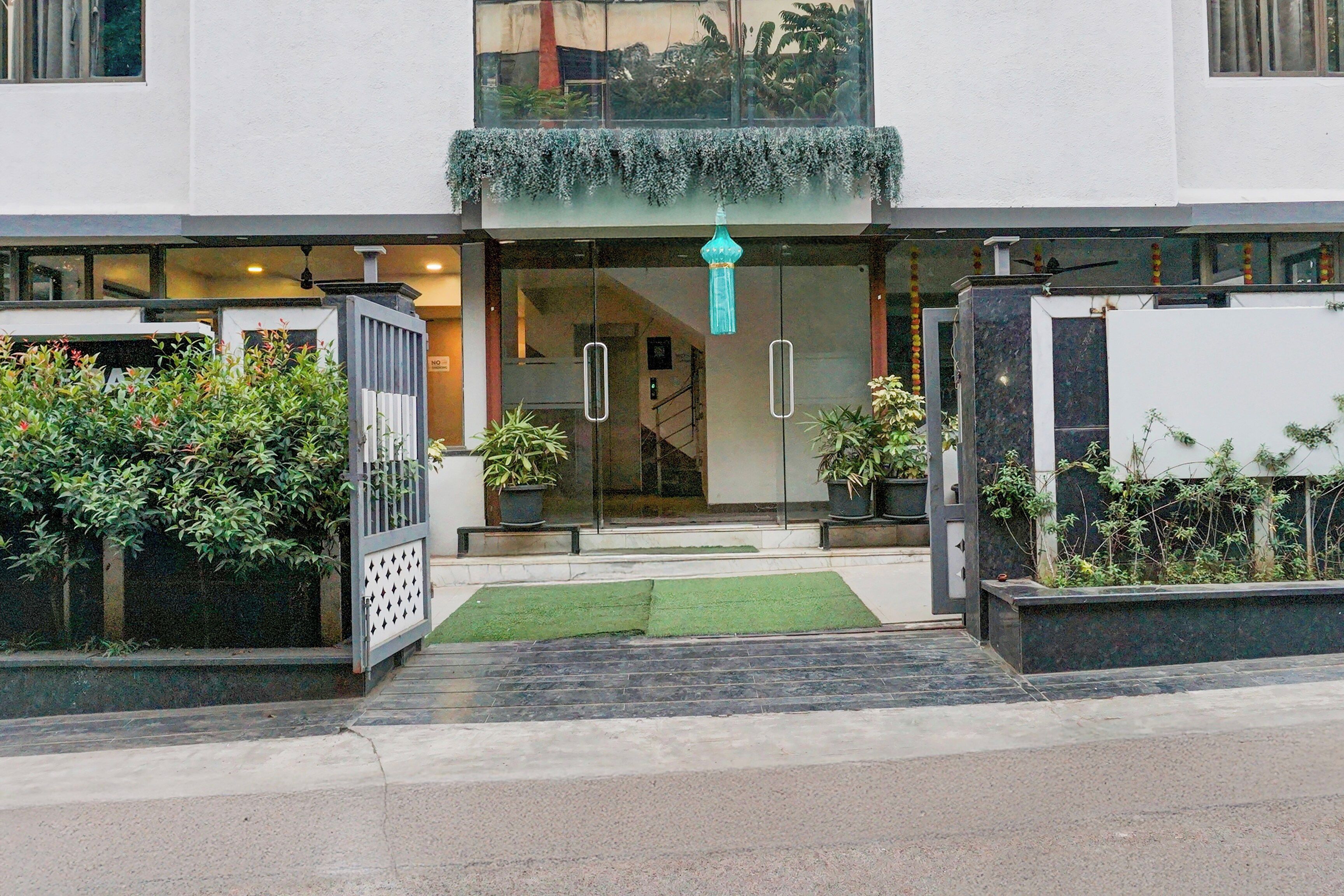 A modern building entrance with a glass door, a green awning, and potted plants.