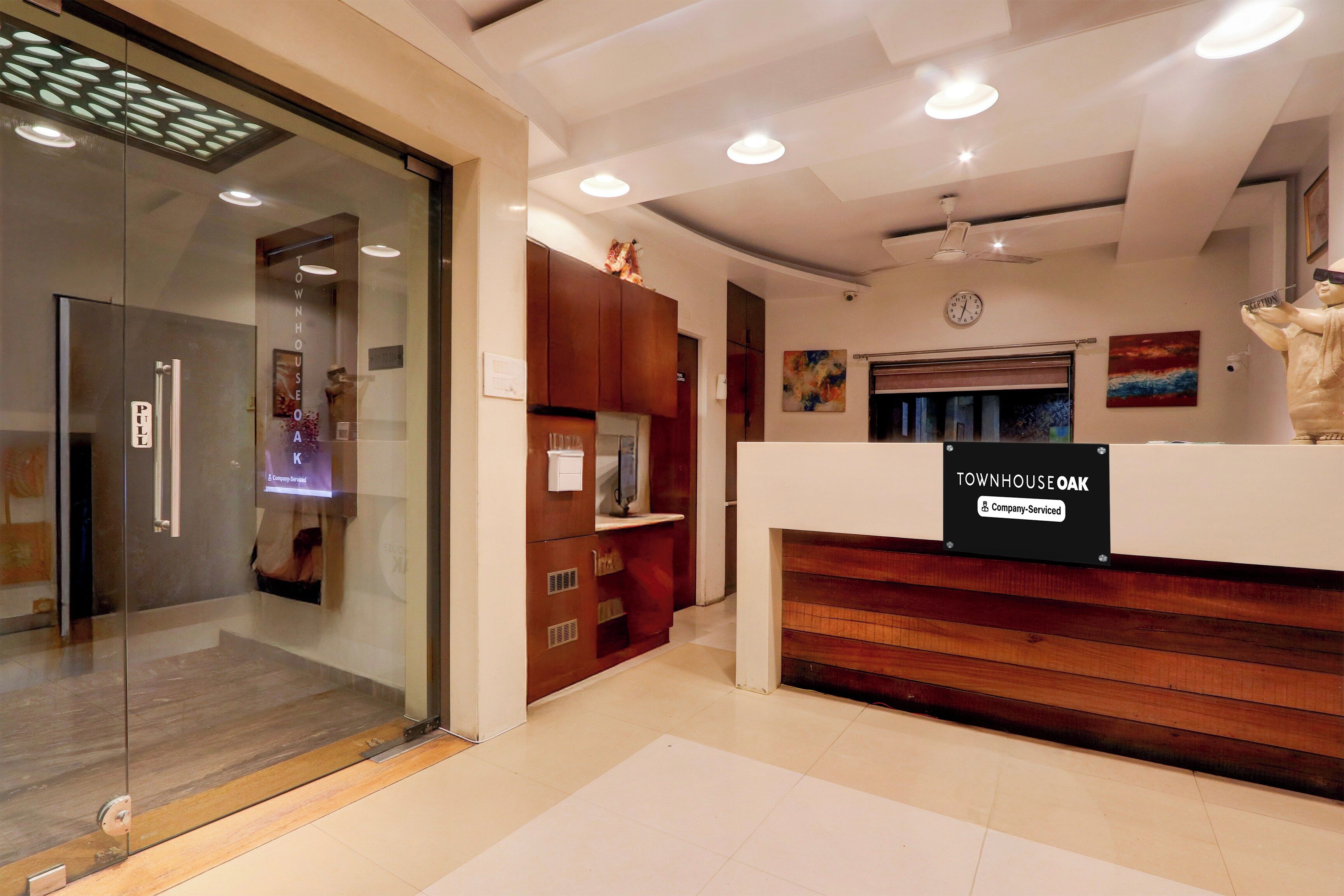 A reception area with a glass door entrance, wooden reception desk, and a clock on the wall.