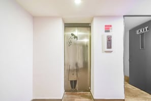 Un ascensor amb un panell de control digital, un senyal de protecció contra incendis i un senyal de sortida.