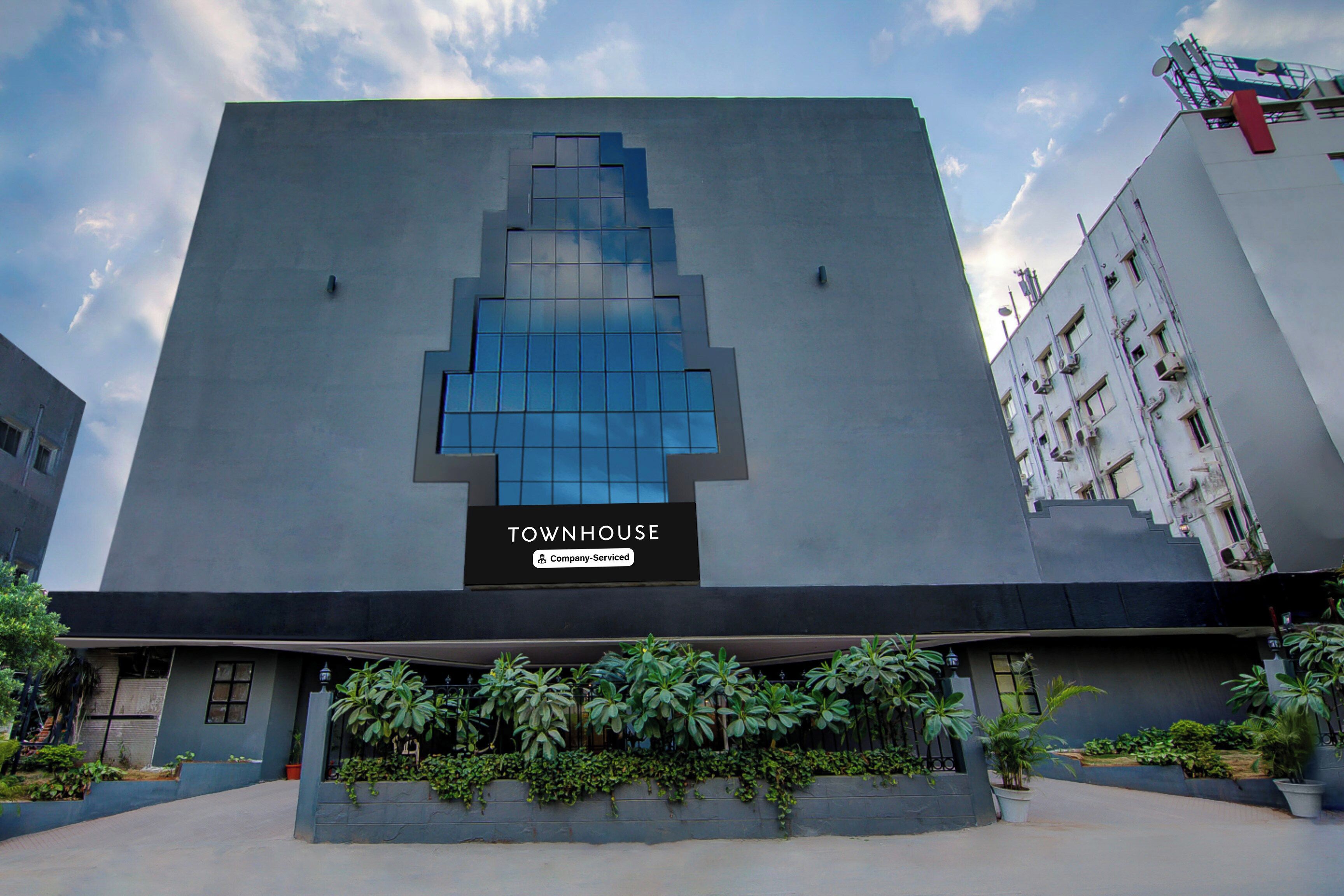Un edificio con un letrero grande que dice 'TOWNHOUSE' y un rótulo de servicio de la empresa.