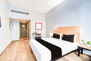 A hotel room with a bed, bedside table, chair, and a small desk with a lamp. - Townhouse Lakdikapul (Hyderabad)