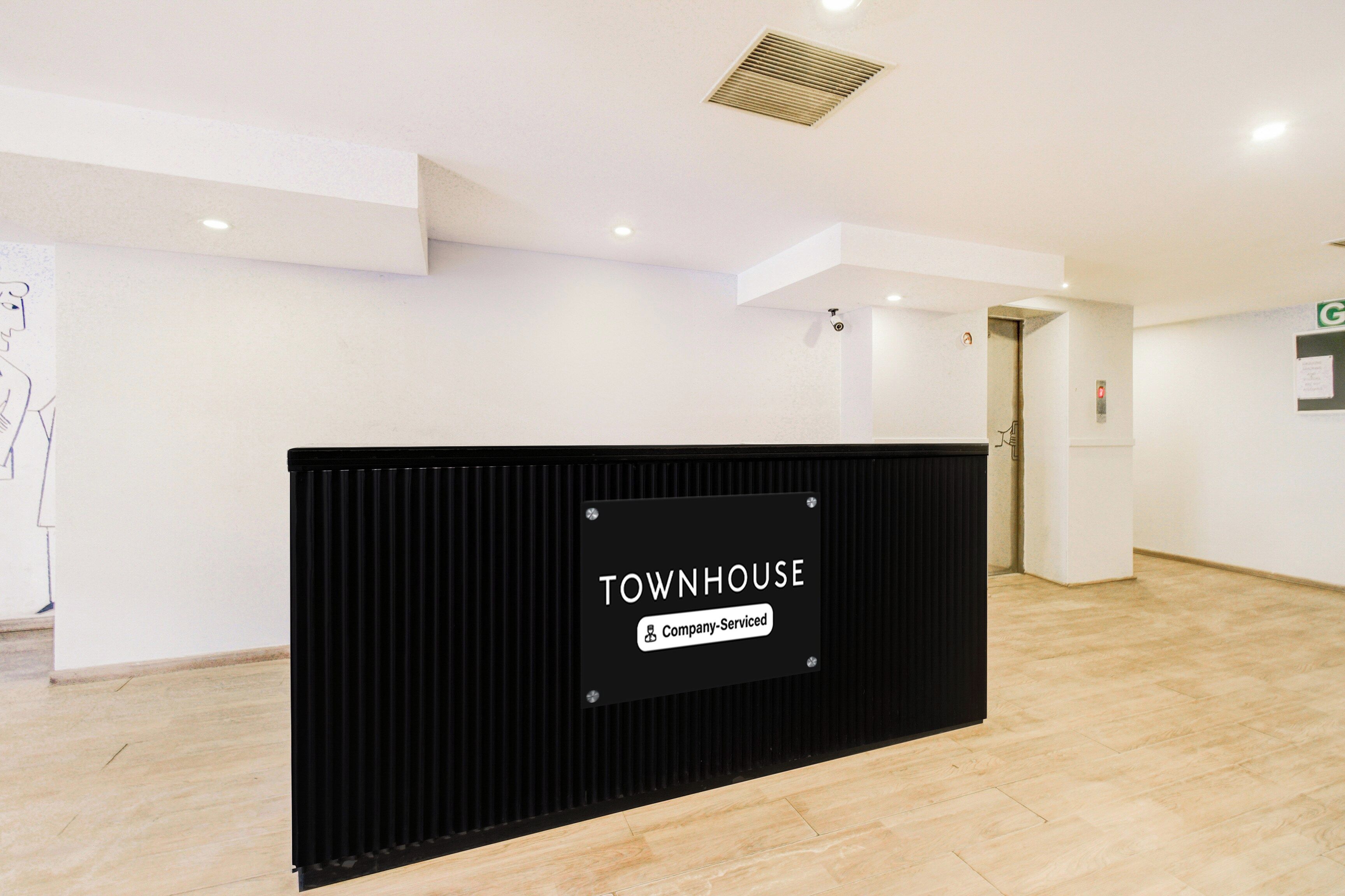 A reception area with a black counter labeled 'TOWNHOUSE' and a sign indicating 'Company-Serviced.'