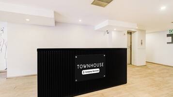 A reception area with a black counter labeled 'TOWNHOUSE' and a sign indicating 'Company-Serviced.'