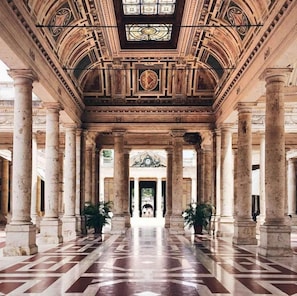 Un salón imponente con techo alto, amplias columnas y un arco central.