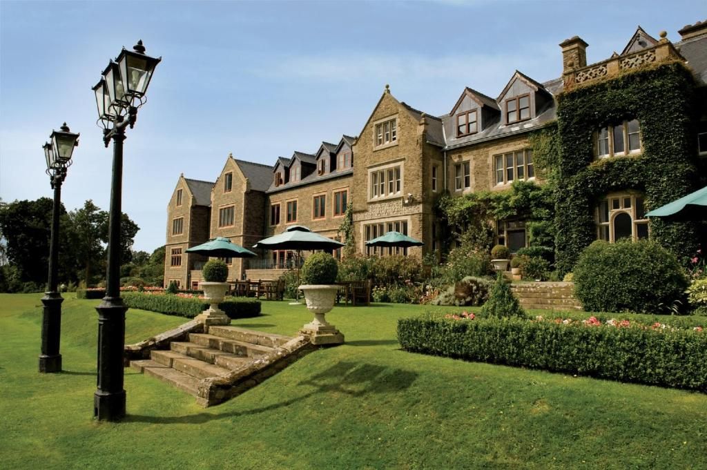 A historic building with a formal garden, stone steps, and outdoor seating areas.