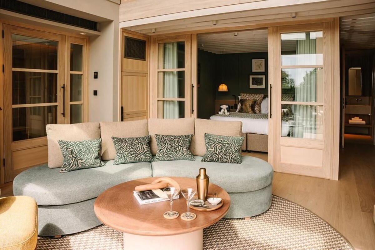 A modern living room with a curved sofa, a coffee table, and a view through large glass doors.