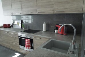 A modern kitchen with a built-in oven, a stainless steel sink, and a red coffee maker. - Holiday apartment with 2 bedrooms (Mittenwald)