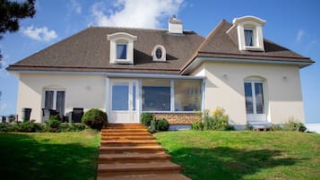 A two-story house with a front porch, a chimney, and a large window.