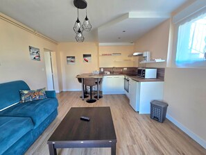 A compact living space with a kitchenette, a dining area, and a sofa. - Apartment 'Escapade En Bord De Mer' with Private Terrace and Wi-Fi (Saint-Côme-de-Fresné)