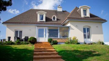 Une maison à deux étages avec un porche à l’avant, une cheminée et une grande fenêtre.
