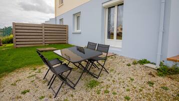 Eine Terrasse mit Tisch und Stühlen, ein Holzzaun und ein Gebäude mit Fenstern.