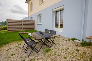 A patio with a table and chairs, a wooden fence, and a building with windows. - Apartment 'Escapade En Bord De Mer' with Private Terrace and Wi-Fi (Saint-Côme-de-Fresné)