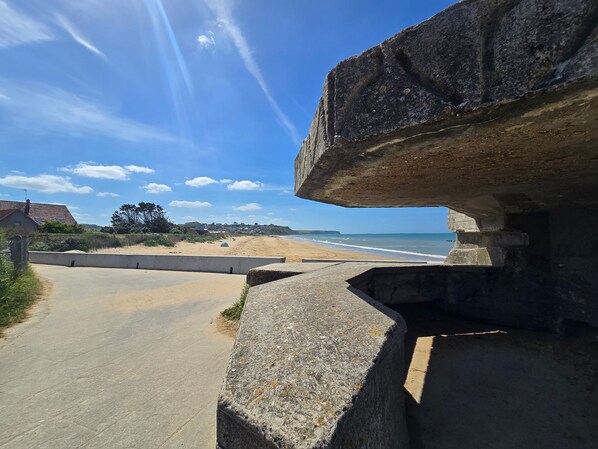 A coastal road with a stone bridge, leading to a beach with houses in the background. - Apartment 'Escapade En Bord De Mer' with Private Terrace and Wi-Fi (Saint-Côme-de-Fresné)
