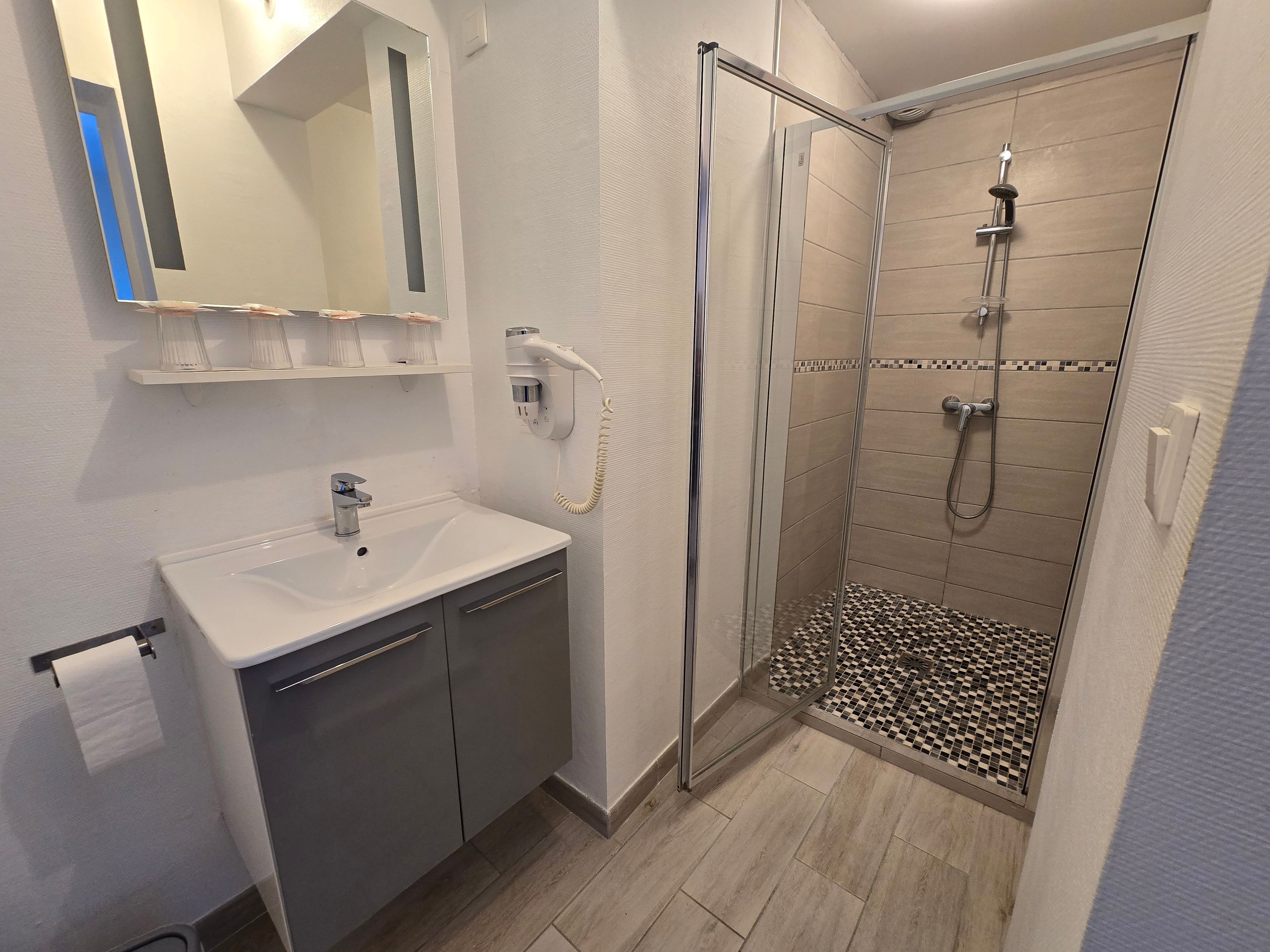Un baño con ducha, lavamanos y espejo.