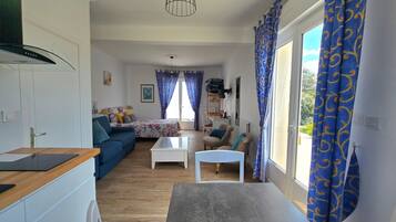 A modern living room with a sofa, coffee table, and a dining area with a table and chairs.