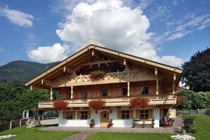 A traditional wooden chalet with a balcony, surrounded by a well-maintained garden and mountains in the background. - Alpspitz at the Grasegger holiday home (Garmisch-Partenkirchen)