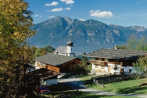A mountain village with traditional wooden houses, a church, and a clear view of the surrounding mountains. - Alpspitz at the Grasegger holiday home (Garmisch-Partenkirchen)
