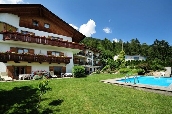 A multi-story hotel with balconies, a swimming pool, and a well-maintained lawn. - House Rosengarten C&D (Dorf Tirol)