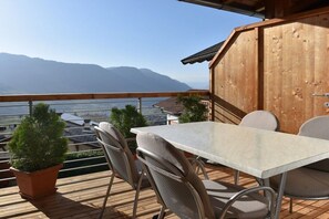 A wooden deck with a table and chairs, overlooking a mountainous landscape. - House Rosengarten C&D (Dorf Tirol)