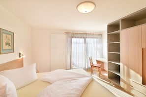 A hotel room with a bed, a chair, a wardrobe, and a window with curtains. - House Rosengarten C&D (Dorf Tirol)
