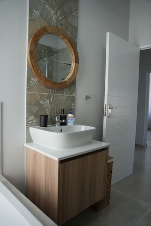 Un baño con un lavamanos blanco, un mueble de madera y un espejo con marco de madera.