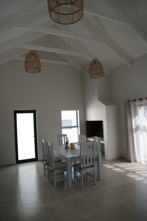 A spacious dining area with a high ceiling, white walls, and a fireplace. - Home from home with an indoor braai, 700 m to the Golden Mile (Saint Helena Bay)