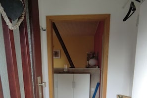 Ein Durchgang zu einem Raum mit einem weißen Schrank und einem blauen Besen.