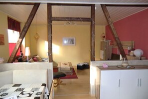 A room with a wooden ceiling, a bed with a red blanket, a table with a lamp, and a cabinet with a mirror. - Holiday apartment with 1 bedroom (Oberhausen)