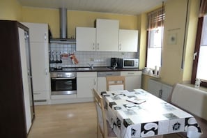 A compact kitchen with white cabinets, a microwave, and a dining table set for two. - Holiday apartment with 1 bedroom (Oberhausen)
