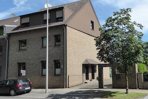 A two-story brick building with a flat roof, a gated entrance, and a tree in front. - Holiday apartment with 1 bedroom (Oberhausen)