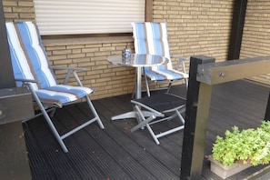 A patio area with two striped lounge chairs, a small round table, and a potted plant. - Holiday apartment with 1 bedroom (Oberhausen)