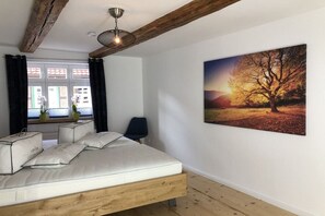 A bedroom with a bed, a window with curtains, a chair, and a painting on the wall. - Mountain apart 4||Wernigerode (Wernigerode)