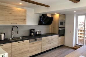 A modern kitchen with a built-in microwave, oven, and a flat-screen TV mounted on the wall. - Mountain apart 4||Wernigerode (Wernigerode)