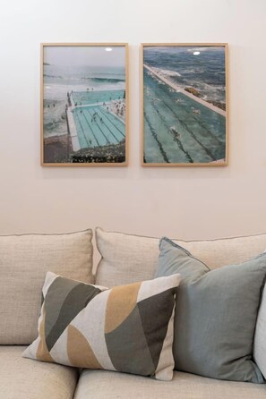 A framed photograph of a swimming pool with people, mounted on a wall above a sofa with cushions. - Paddington 3BR Terrace | North-Facing Courtyard (Paddington)