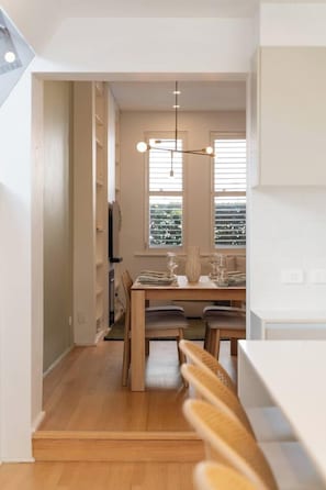 A modern kitchen with a dining area, wooden flooring, and a pendant light. - Paddington 3BR Terrace | North-Facing Courtyard (Paddington)