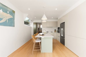 A modern kitchen with a central island, white cabinetry, and a stainless steel refrigerator. - Paddington 3BR Terrace | North-Facing Courtyard (Paddington)
