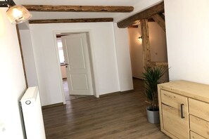 A hallway with wooden beams, a white door, a potted plant, and a wooden cabinet. - Mountain apart 5||Wernigerode (Wernigerode)